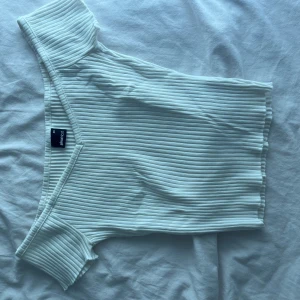 Vit ribbad topp från Gina Tricot XS - Säljer en vit ribbad topp från Gina Tricot i storlek XS. Toppen har korta ärmar och en snygg, figurnära passform. Perfekt att styla med jeans eller kjol för en clean look. Materialet är mjukt och stretchigt för extra komfort.