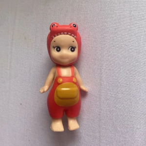 Sonny Angel - Bilderna visar en söt leksaksfigur i röd dräkt med djurhuva och svans, men ingen bok syns på bilderna.