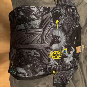 Nike Brasil Dri-FIT fotbollströja M - Unik Brasilien fotbollströja från Nike med svart och grått konstnärligt tryck av Kristusstatyn och brasilianska symboler. Gula detaljer, Brasil-logga och Nike Swoosh. Tillverkad i Dri-FIT-material som andas. Kortärmad och perfekt för dig som vill sticka ut på planen.