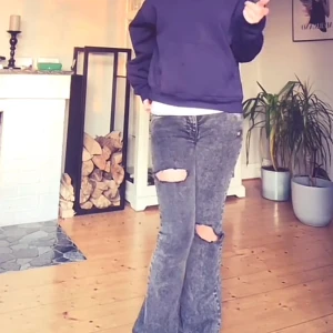 Grå bootcut jeans med slitningar - Säljer ett par grå bootcut jeans med coola slitningar över knäna. Jeansen har en tvättad look och är i klassisk femficksmodell. Perfekta för dig som gillar en avslappnad och trendig stil.