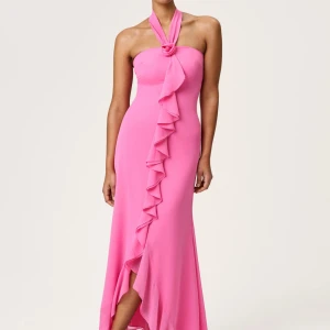  Adoore Lamia dress - Supersnygg rosa långklänning från Adoore med halterneck och volangdetalj framtill. Klänningen har en elegant omlottkänsla och en rosformad knut vid halsen. Perfekt för dig som vill sticka ut med en feminin och trendig look.