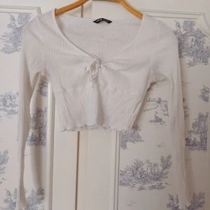 Vit ribbad croppad topp från Shein - Säljer en vit ribbad croppad topp från Shein med långärmade ärmar och knytning framtill. Perfekt för en stilren look. 🖤