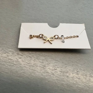 Guldhalsband med rosett - Elegant guldhalsband med en fin rosettdetalj i mitten. Perfekt för att lägga till en subtil touch av stil till din outfit. Halsbandet har en justerbar kedja för att passa olika storlekar.