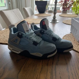 Nike Air Jordan 4 university blue - Snygga Nike Air Jordans i ljusblå mocka med svarta och vita detaljer. Skorna har snörning och en ikonisk Jumpman-logga på hälen. Perfekta för dig som vill ha en stilren och sportig look. Först till kvarn 