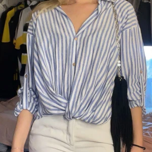 Blå- och vitrandig blus - Säljer denna stilrena skjorta från Zara. Den har en slags insydd ”knytning” vid magen💙 Storlek S