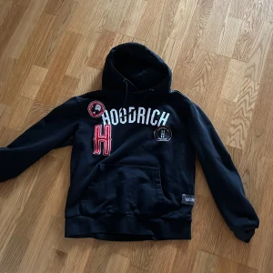 Svart hoodie från Hoodrich - Säljer en svart hoodie från Hoodrich med coola broderade detaljer i rött och vitt. Den har en stor ficka framtill och en justerbar huva med snören. Perfekt för en avslappnad stil. Jag står ej för frakt!!!!! Öppen för prisförslag.