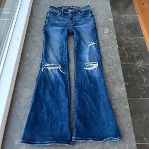 American Eagles bootcut jeans  - Säljer ett par så så fina bootcut jeans från american Eagle med hål vid knäna💕Midjemåttet är 36 cm och innerbenslängden 73 cm, men jeansen har mycket strech så passar flera storlekar💕