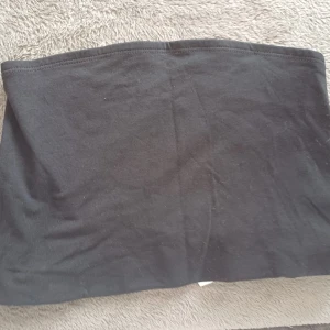 Svart tubtopp från Divided - Säljer en enkel och stilren svart tubtopp från Divided. Perfekt för att matcha med olika outfits. Gjord i ett mjukt och bekvämt material.