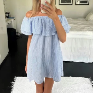 Randig offshoulder klänning - ❣️lånad första bild❣️Söt och luftig offshoulder klänning med blå och vita ränder. Perfekt för varma dagar med sin avslappnade passform och volangdetalj vid axlarna. Enkla ränder ger en klassisk look. Med fickor!!