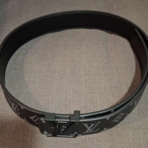 Svart bälte med monogram - Snyggt svart bälte med det klassiska monogrammönstret. Bältet har en stilren design med en metallspänne som pryds . Perfekt för att ge en lyxig touch till din outfit. Storleken 105cm