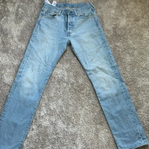 Levis 501 ljusblå jeans - Säljer ett par klassiska Levis 501 jeans i ljusblå denim. De har en rak passform och är tillverkade i slitstarkt jeansmaterial. Perfekta för en avslappnad stil.