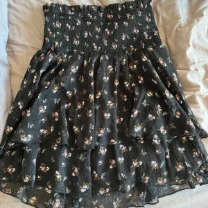 Svart blommig kjol - Söt blommig volang kjol från bikbok! Mycket sparsamt använd, kjolen går även att ha som topp (se bild 2) storlek S🩷perfekt till sommaren! 