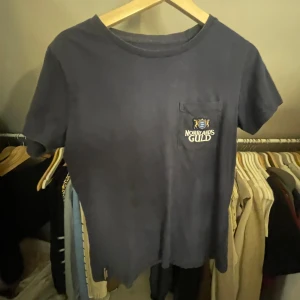 Mörkblå t-shirt med Norrlands Guld-tryck - Säljer en mörkblå t-shirt med ett coolt Norrlands Guld-tryck på bröstfickan.  De är storlek L men den sitter som en xs-s 