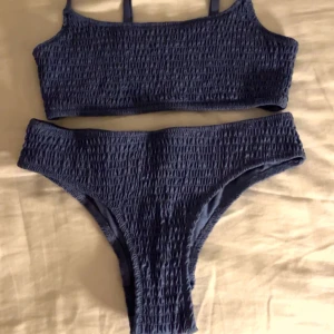 Blå bikini från Kappahl - Snygg blå bikini från Kappahl med en ribbad textur. Toppen har smala axelband och en enkel design. Perfekt för en dag på stranden eller vid poolen. Underdelen har en klassisk passform som matchar toppen.🥰