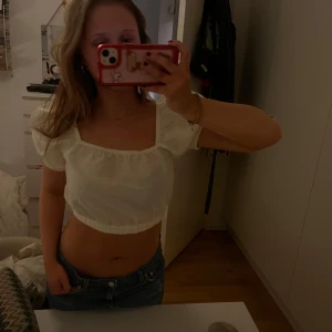 Vit croppad blus - Säljer en söt vit croppad blus med puffiga korta ärmar. Blusen har en fyrkantig urringning och elastiska kanter för en bekväm passform. Endast använd en gång. 