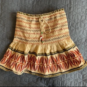 Superfin kjol från Zara - Beige kjol från Zara med mönstrade detaljer nertill och shorts på insidan. Superbra skick och perfekt till sommaren!