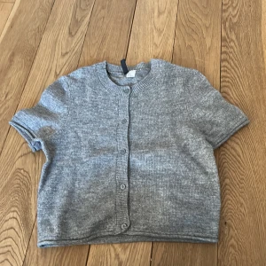 Grå kofta från H&M Divided - Säljer en stilren grå kofta från H&M Divided. Den har korta ärmar och knappar framtill. Perfekt för lager-på-lager och passar till många olika outfits. 🩶