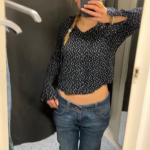 Mörkblå prickig topp - Säljer en mörkblå topp med vita prickar. Toppen har en v-ringad hals och långa ärmar. Perfekt för en avslappnad stil.