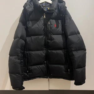 Svart dunjacka från Polo Ralph Lauren - Säljer denna feta raplh lauren jackan🔥.Jackan är i bra skick förutom att den har två små hål som man kan se i sista bilden. annars är jackan i mycket bra skick. Skriv till mig om mer funderingar om jackan, kan gå ner i pris vis snabb affär