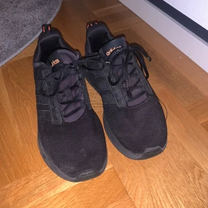 Svarta Adidas sneakers med orange detaljer - Snygga svarta Adidas sneakers med orange detaljer och snörning. Skorna har en sportig design med märkets logga på hälen och sulan. Perfekta för en casual look eller träning. Helt okej pris därav pris 