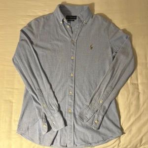 Blå oxfordskjorta från Ralph Lauren - Klassisk ljusblå oxfordskjorta från Ralph Lauren med broderad logga på bröstet. Den är i ny skick och endast använd ett fåtal gånger. Nypris: 1500 kr | mitt pris: 399 kr