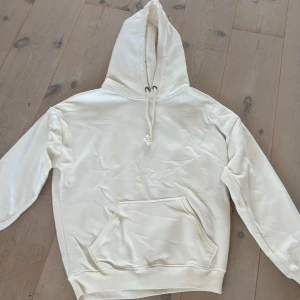 Vit hoodie från BikBok med huva - Säljer en stilren vit hoodie från BikBok i storlek XS. Tröjan har huva med snörning. Perfekt för en chill look och passar till allt. Mjuk och skön, använt 1 gång 