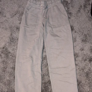 Grå mjukisbyxor med snörning - Säljer ett par grå mjukisbyxor med elastisk midja och snörning. Lite noppriga. Byxorna har raka ben, två fickor fram och två bak. Perfekta för chill dagar eller när du vill vara extra bekväm. Materialet är mjukt och skönt mot huden.