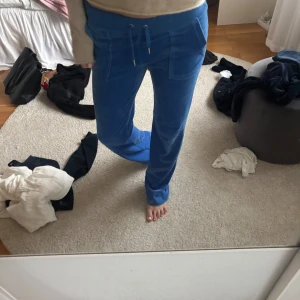 Blå velourbyxor Juicy Couture - Säljer ett par blåa mjukisbyxor från Juicy Couture i mjuk velour.Inte alls mycket använda! Klassisk Juicy Couture-logga broderad på ena fickan. Perfekta för en chill och trendig look.