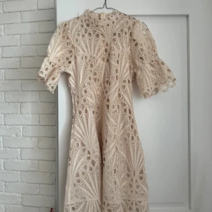 Beige spetsklänning med volangärm - Superfin kortklänning i beige med unik broderad spets och coola hålmönster. Lappen är borta men köpt på byic förra sommaren❣️