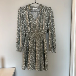 Blommig Designers Remix klänning  i superfint skick  - Supersöt klänning från Designers Remix i grönt och vitt med blommigt mönster. Klänningen har v-ringning, smockad krage och midja, volangdetaljer och långa ärmar med rynkade muddar. Perfekt inför höstens fester!  Size 12 år. ( känns som 146-152 i storlek ) 