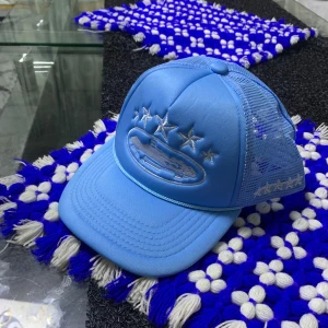 Corteiz Keps - Snygg ljusblå truckerkeps med mesh på sidorna och broderade stjärnor framtill och på sidan. Framsidan har även ett broderat motiv av en bil. Perfekt för dig som vill sticka ut med en cool accessoar.