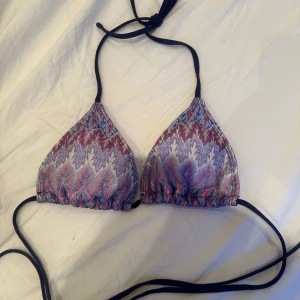 Mönstrad bikiniöverdel med knytband - Snygg bikiniöverdel med ett färgglatt mönster i blått, rosa och lila. Den har knytband i mörkblått runt nacken och ryggen för justerbar passform. Perfekt för en dag på stranden eller vid poolen💓😊