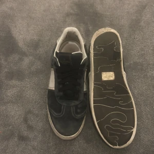 Valentino Flycrews - Snygga Valentino Garavani sneakers i svart och vitt skinn med klassisk låg profil och svarta snören. Skorna har rund tå, platt sula och diskret logga på plösen. Perfekta för dig som gillar exklusiva och stilrena sneakers. Kommer utan box och skon har gått av lite från sulan