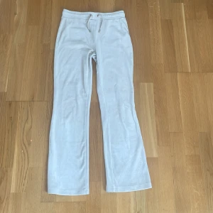 Beigea mjukisbyxor från Gina Tricot - Supermjuka beiga mjukisbyxor från Gina Tricot med bootcut-ben och snörning i midjan. Byxorna har två bakfickor och är gjorda i ett skönt velour. Perfekta för chill dagar eller när du vill vara extra bekväm.