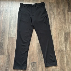Svarta kostymbyxor Jack & Jones slim HELT NYA - Jag köpte dessa men de var för små och jag hade tagit bort etiketten så jag kunde inte returnera. Alldrig använda helt nya. Köpt från Zalando. Svarta kostymbyxor från Jack & Jones i slim fit-modell. Byxorna har klassisk design med hällor för bälte, snedställda fickor fram och två bakfickor. Perfekta för en clean och stilren look. 