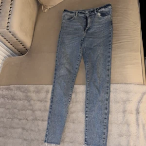 Blå skinny jeans - Snygga ljusblå skinny jeans med råa, fransiga benslut. Klassisk femficksmodell med dragkedja och knapp i midjan. Jeansen har en smal passform och är tillverkade i mjukt denimtyg som sitter tajt men bekvämt.