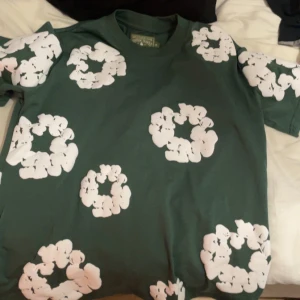 Gröna shorts med vit blommig print - Snygga gröna shorts med stora vita blommiga mönster över hela tyget. De har elastisk midja med snörning och sidofickor, perfekta för chill dagar. Mjukt material som känns skönt mot huden och ger en avslappnad vibe.