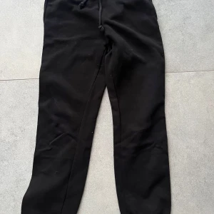 Svarta mjukisbyxor med snörning - Svarta mjukisbyxor med dragsko i midjan. Sköna och avslappnade, perfekta för chill eller träning. Tillverkade i mjukt material som känns bekvämt hela dagen.