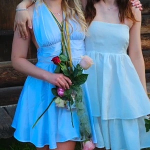 Vit kortklänning från Bubbleroom  - Supersöt vit kortklänning från Bubbleroom i halterneck-modell med djup v-ringning och knyt i nacken samt midjan❤️ Klänningen har ett flowy tyg i polyester och markerad midja som ger en snygg siluett🥰Endast använd 1 gång på en skolavslutning