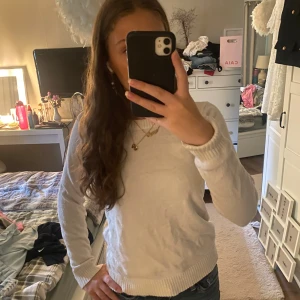 Vit stickad tröja från Vila - En enkel och fräsch vit stickad tröja från Vila. Tröjan har rund halsringning, ribbade muddar och är långärmad. Perfekt att slänga på sig till jeans eller kjol för en clean look.