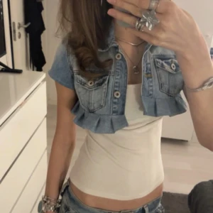 Croppad jeansväst med volangkant - Säljer en croppad ljusblå jeansväst med volangkant nertill. Jättefin till outfits! I xs/s💞