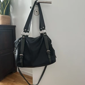 Svart axelväska med dragkedjor - Snygg svart axelväska i skinnimitation med flera fack och dragkedjor. Väskan har dubbla handtag, justerbar axelrem. Skriv privat för mer detaljerade bilder osv.