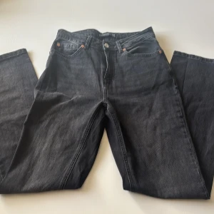 Jeans från Stradivarius - Säljer ett par svarta jean från Stradivarius med klassisk femficksdesign och raka ben. Byxorna har normal passform, knapp och dragkedja framtill samt bälteshällor. Perfekta till din vardagsstil.