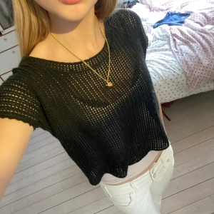 Svart nätstickad croppad topp från BikBok - Säljer en svart nätstickad croppad topp från BikBok. Toppen har korta ärmar och är tillverkad i ett luftigt, stickat material som ger en cool och avslappnad look. Perfekt att styla över ett linne eller bikini.