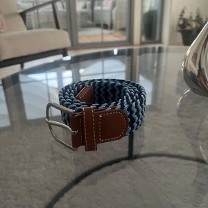 Blått flätat bälte  - Tja Säljer ett snyggt blått flätat bälte med bruna skinn-detaljer vid spännet. Bältet är köpt på Kidsbrandstore och aldrig använt. Nypris 349kr. Vid minsta lilla fundering tveka inte på att höra av er!