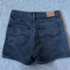 Svarta jeansshorts från Lee - Klassiska svarta jeansshorts från Lee med hög midja. Perfekta för sommaren och enkla att matcha. Seljer dessa shorts eftersom de inte passar! Nästan helt oanvända och inga tecken på användning🥰🥰
