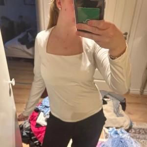 Vit långärmad topp från H&M - Säljer en enkel och stilren vit långärmad topp från H&M. Toppen har en fyrkantig urringning och är figurnära i modellen. Perfekt att matcha med både jeans och kjol.