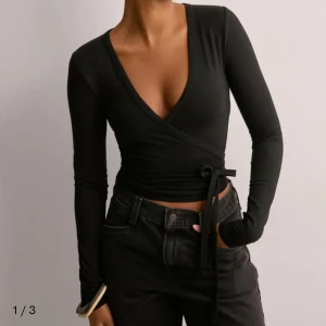 Svart omlottopp med knytband - Säljer min Tie wrap soft top från Nelly då den inte passade mig, använt 1-2 gånger🥰
