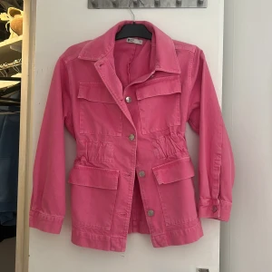 Rosa utilityjacka från g perfect jeans - Säljer en rosa utilityjacka från g perfect jeans i storlek XS. Jackan har flera stora fickor framtill, knappar och markerad midja med resår. Perfekt för dig som vill ha en färgstark och praktisk jacka med cool look. Nypris 600, använd några enstaka gånger 