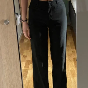 Svarta kostymbyxor från Monki - Snygga svarta kostymbyxor från Monki med normal passform och raka ben. Byxorna har hög midja och klassisk dragkedja med knapp framtill. Perfekta till många olika outfits och enkla att matcha.